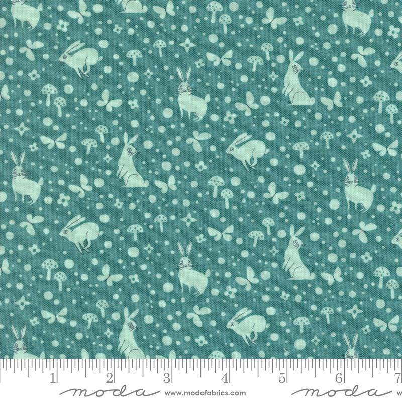 a green fabric with white rabbits and mushrooms on it