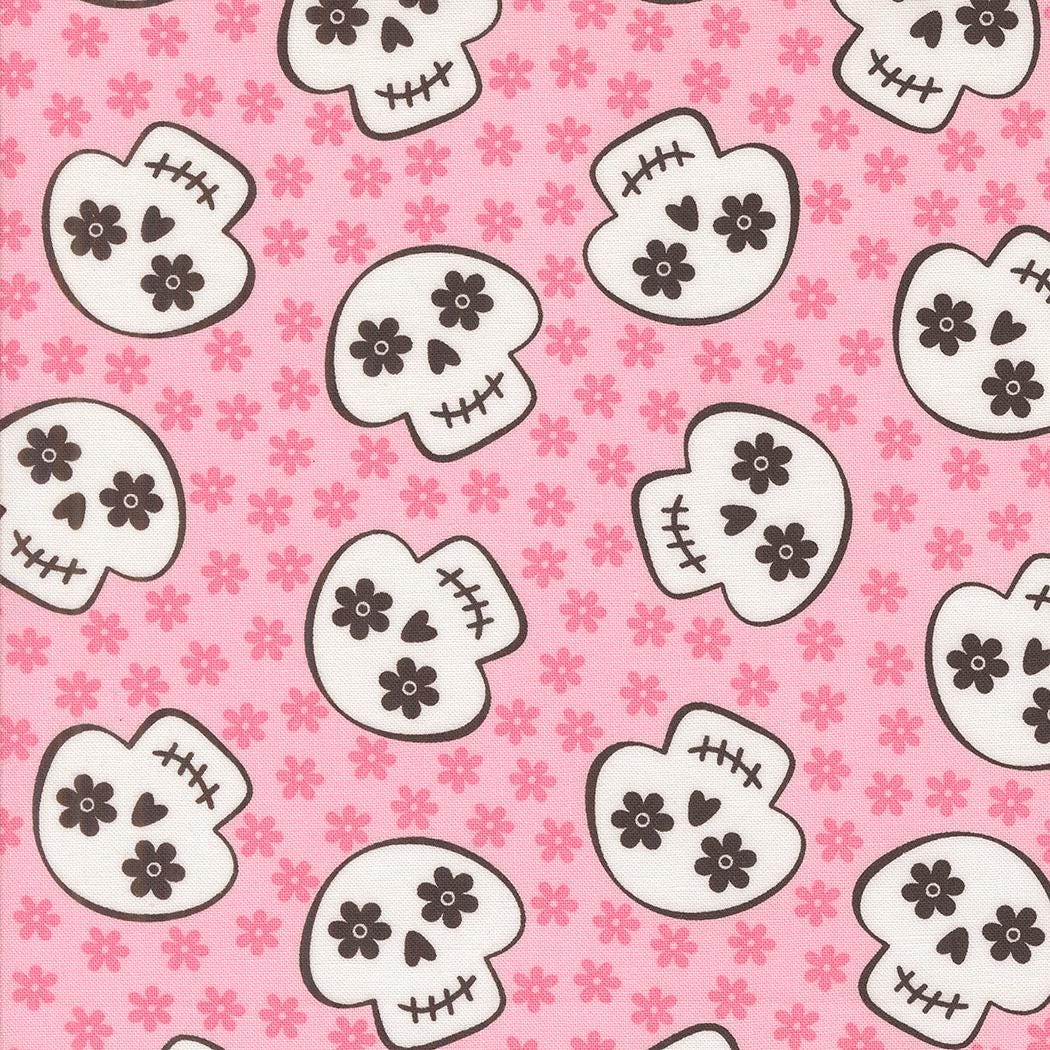 a repeating pattern of stylized skull faces on a pink background with small pink flowers scattered throughout.