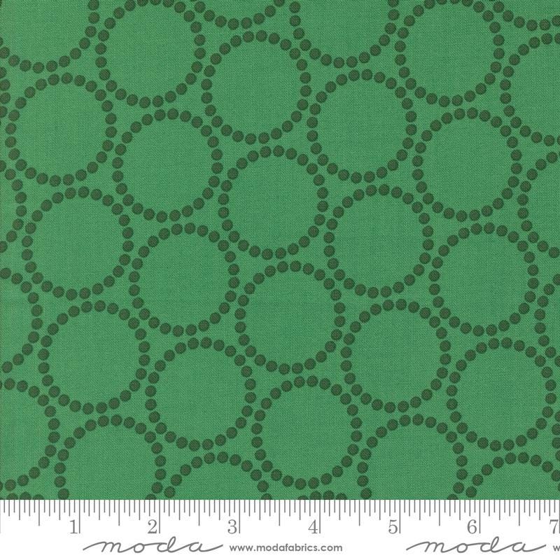 The image is a close-up of a fabric with a repeating pattern of green circles on a dark green background.