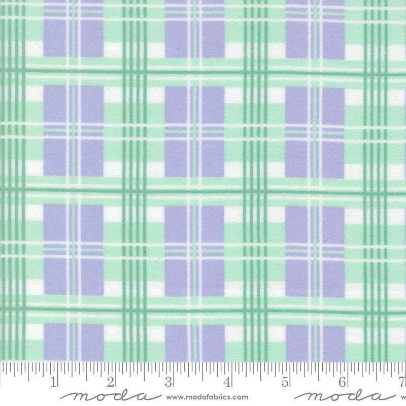 The image is a fabric with a repeating pattern of purple and green plaid squares. The pattern is composed of diagonal lines connecting the squares, creating a visually appealing and textured design. The fabric appears to be made of a soft, plush material, suitable for clothing or home decor items.