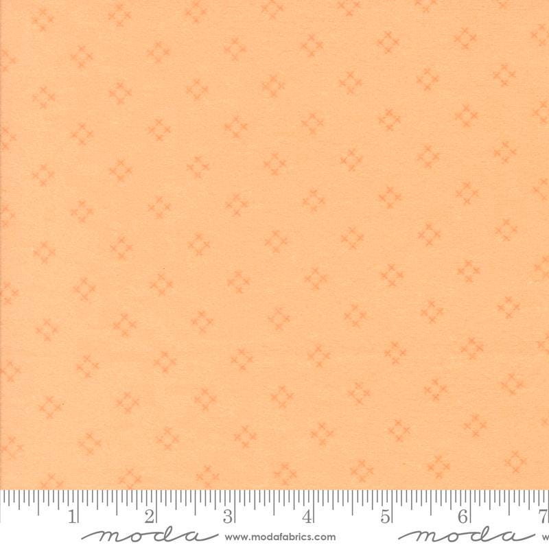 The image is a fabric with a repeating pattern of small orange dots or stars on a light orange background.