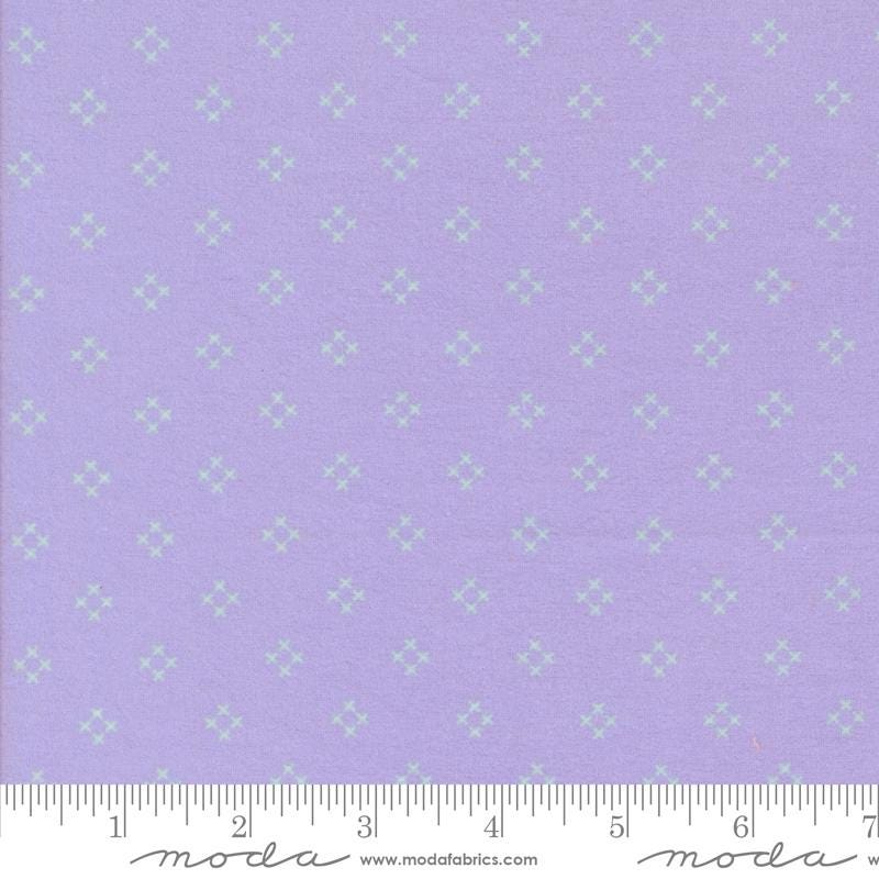 The image is a fabric with a purple background and a repeating pattern of small white stars or diamonds. The fabric appears to be a type of textile, possibly used for clothing or home decor.