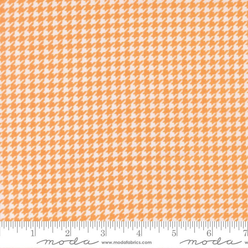 The image is a fabric with a repeating pattern of orange and white houndstooth shapes, creating a textured and visually interesting design.
