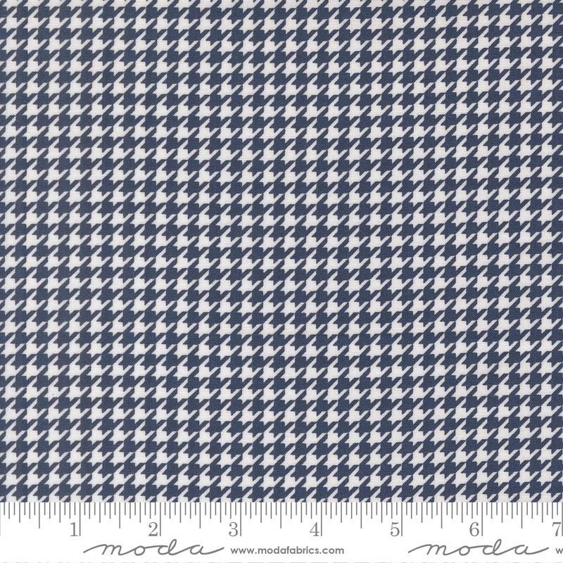 a close-up view of a fabric with a repeating pattern of white and navy blue houndstooth shapes.