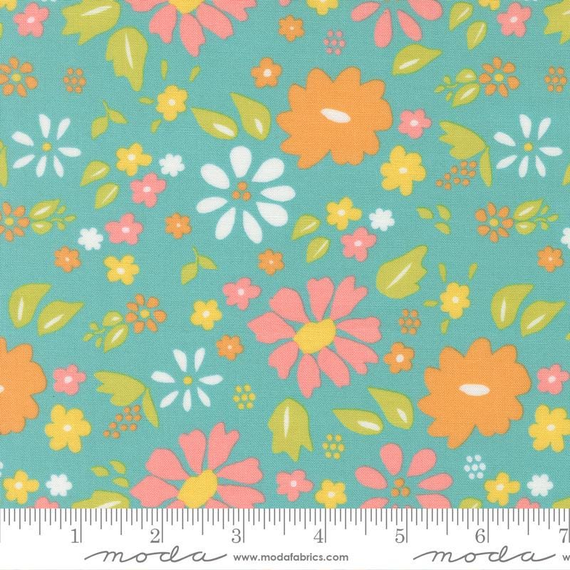 The image is a fabric with a floral pattern in shades of green, orange, and pink. The pattern consists of various flowers and leaves in different sizes and orientations, creating a vibrant and lively design.