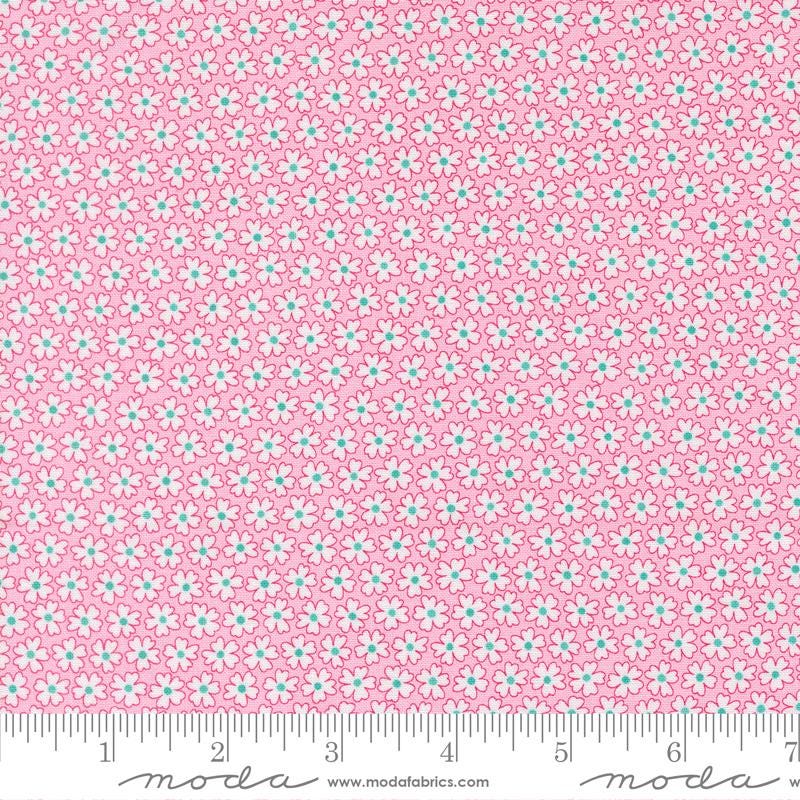 a close-up view of a fabric with a pink floral pattern. The fabric appears to be made of Moda cotton material, as indicated by the text in the image.