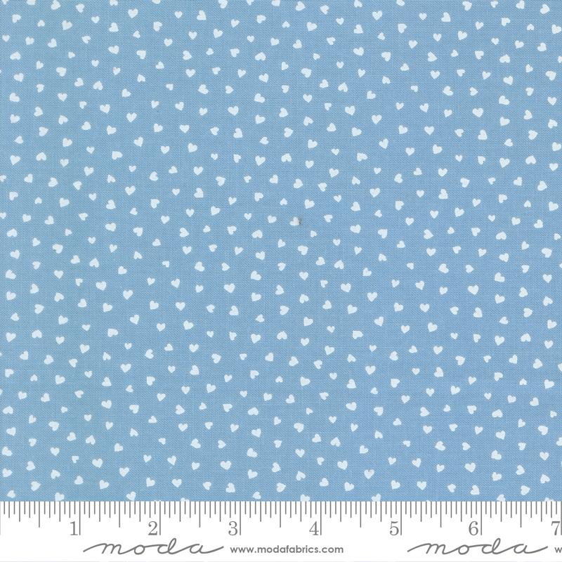 a fabric with a light blue background and white heart-shaped patterns scattered across it. The fabric appears to be a textile or material with a heart-shaped design.