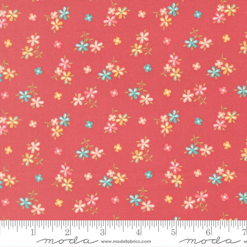 a vibrant red fabric with a repeating pattern of small, colorful flowers in shades of pink, blue, and yellow. The flowers are scattered across the fabric in a random yet visually appealing manner, creating a lively and cheerful design.