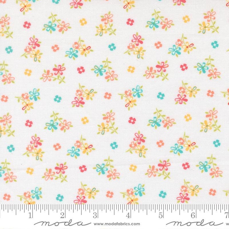 The image is a fabric with a floral pattern, featuring small colorful flowers and leaves scattered across it.