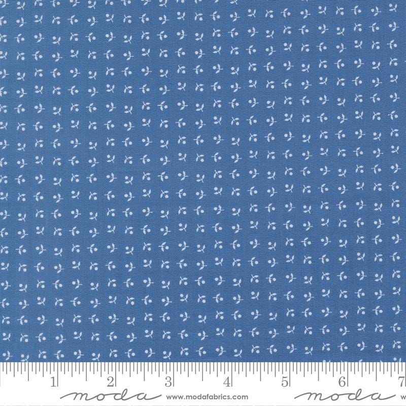 The image is a close-up of a fabric with a blue pattern, featuring small white dots or flowers arranged in a grid-like pattern.