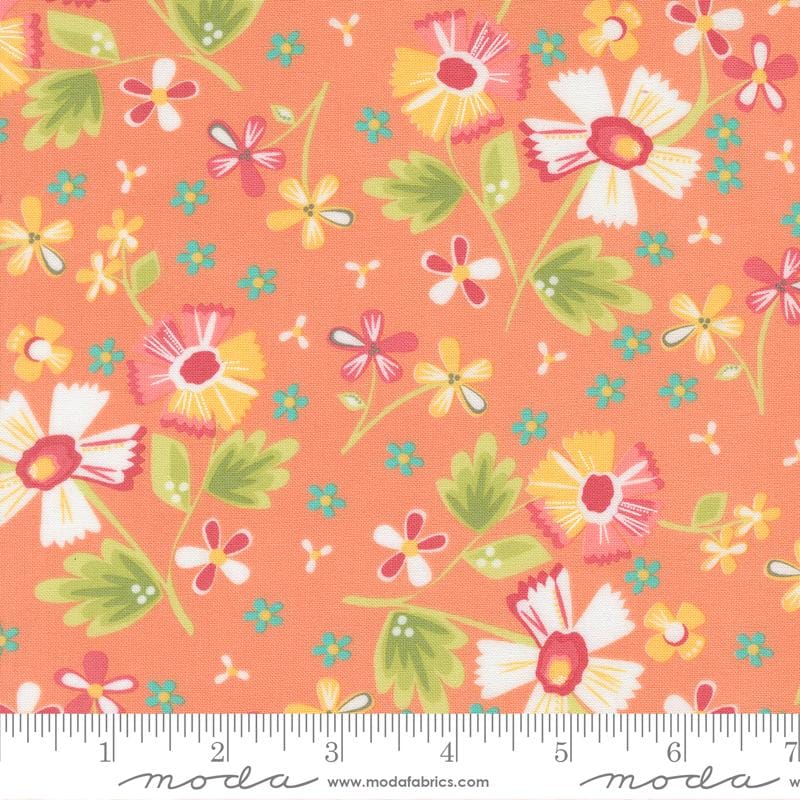 The image is a vibrant and colorful fabric with a repeating pattern of flowers and leaves in shades of orange, yellow, and green. The pattern is composed of various flower shapes and sizes, creating a lively and dynamic visual effect. The fabric appears to be made of cotton and is displayed on a ruler for size reference.