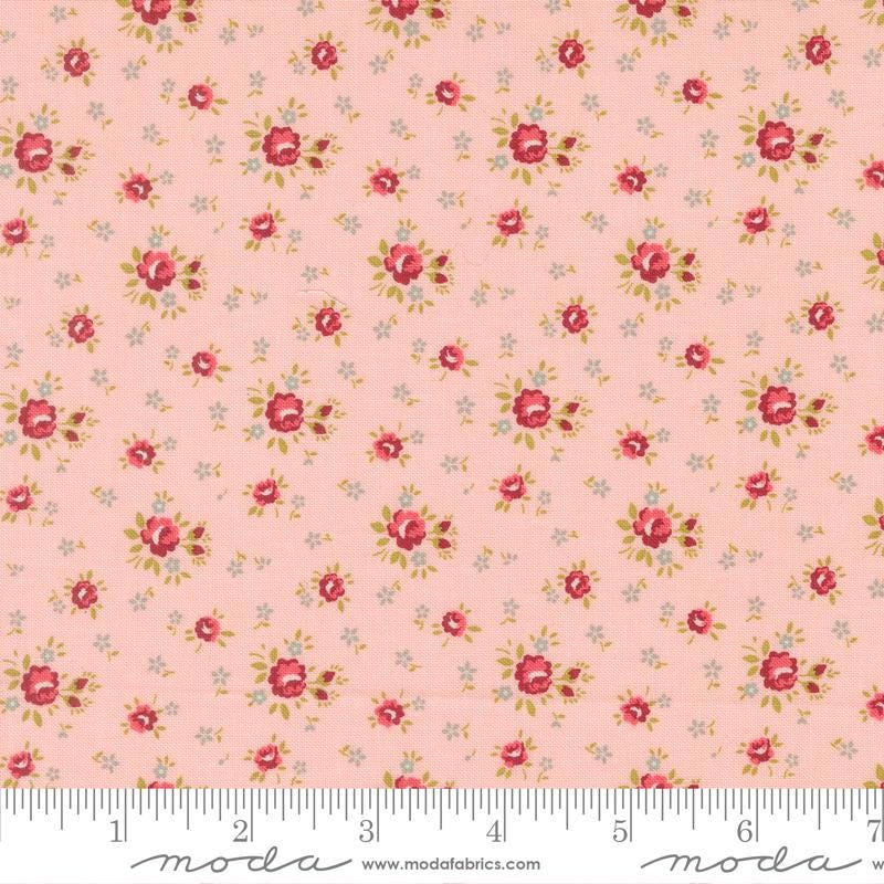 The image is a fabric with a repeating floral pattern in shades of pink and white. The pattern consists of small red flowers and leaves scattered across the fabric, creating a visually appealing and intricate design.