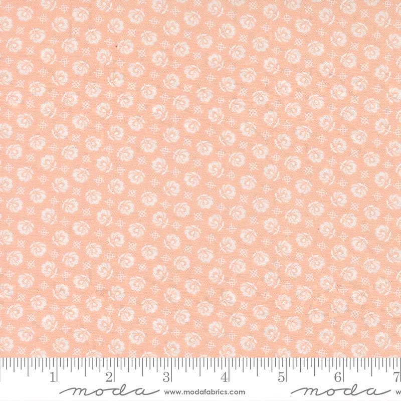 The image is a fabric with a repeating pattern of small white flowers or circles on a peach-colored background.