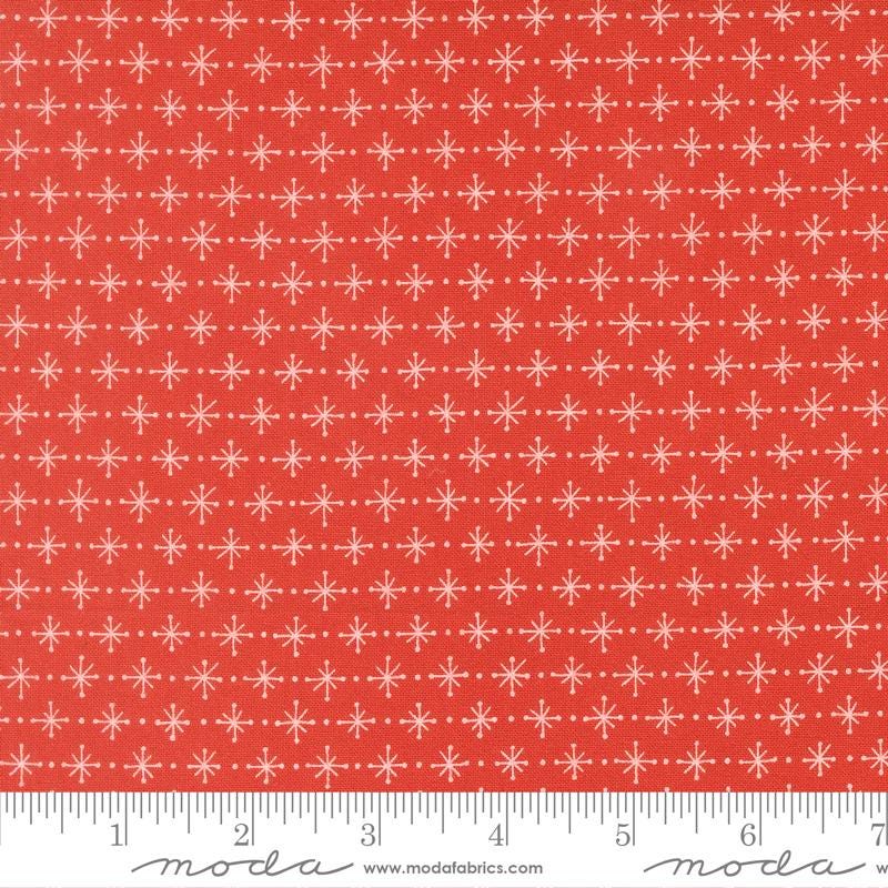 a red fabric with a repeating pattern of white snowflakes. The fabric has a ruler at the bottom to provide a scale for the image.