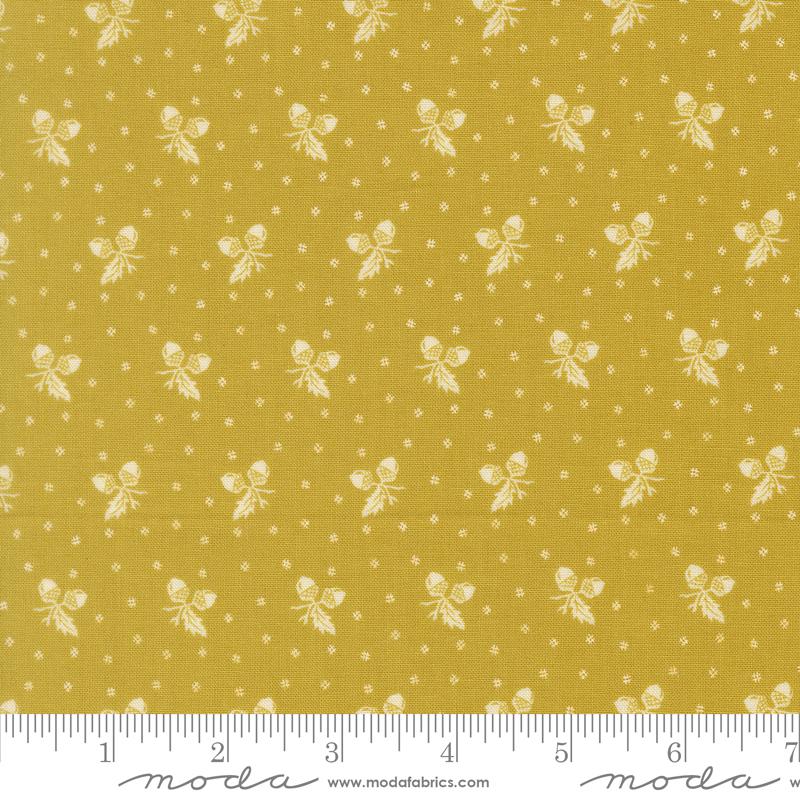The image is a fabric with a repeating pattern of white acorns on a yellow background.