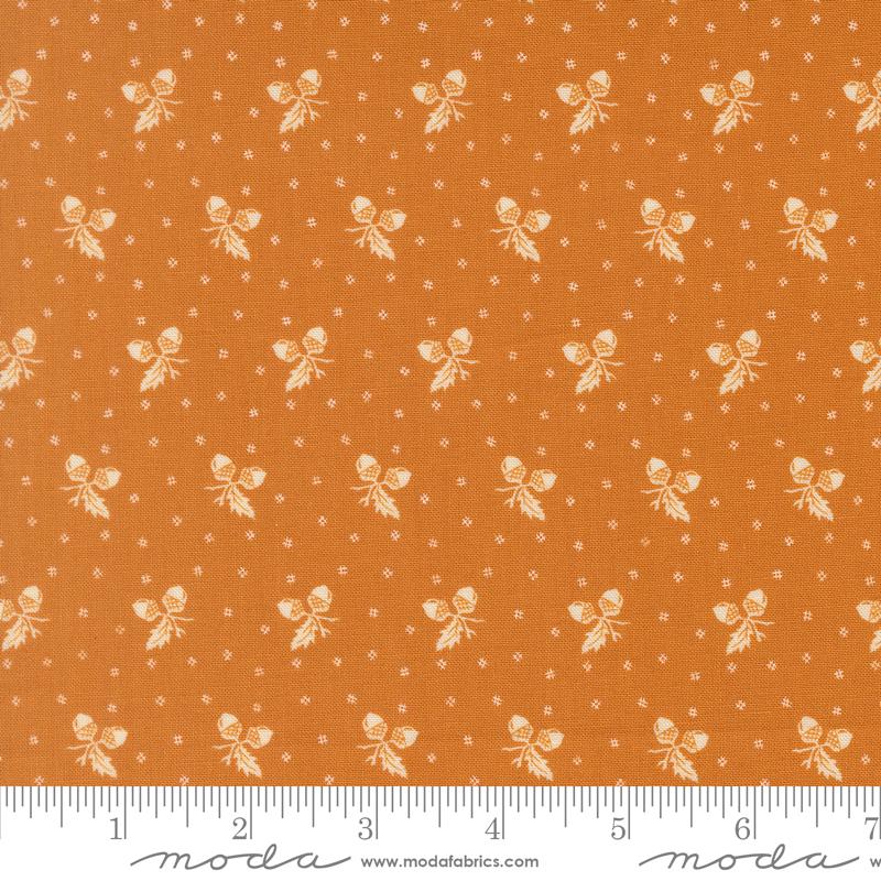 The image is a fabric with a repeating pattern of small white acorns or leaves against an orange background. The pattern is evenly spaced and creates a visually appealing design.