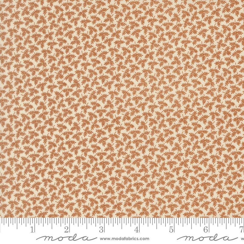 The image is a fabric with a repeating pattern of brown leaves or flowers on a cream-colored background.