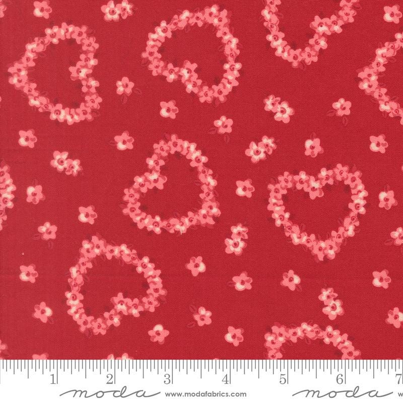 a red fabric with a pattern of pink hearts and flowers scattered across it.