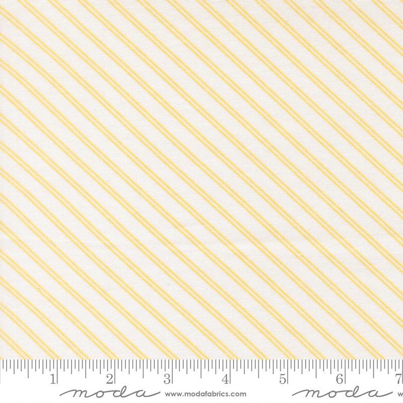 a fabric with diagonal yellow stripes arranged in a repeating pattern. The fabric is white and has a ruler placed at the bottom to indicate its size.