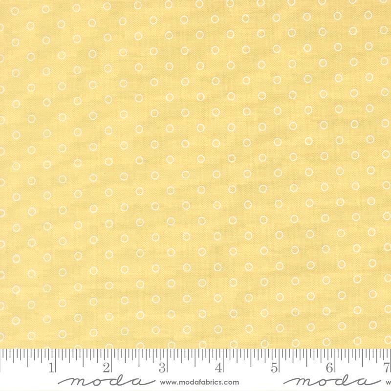 The image is a close-up of a fabric with a yellow background and white polka dots.