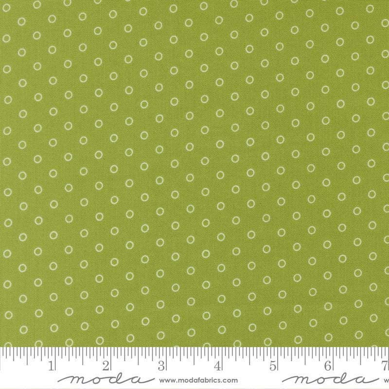 a close-up view of a fabric with a green background and white polka dots. The fabric appears to be a type of textile, possibly used for clothing or home decor.