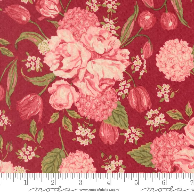 a close-up view of a vibrant red fabric adorned with a floral pattern. The pattern consists of various pink and red flowers, including roses, hydrangeas, and tulips, interspersed with green leaves. The fabric appears to be a textile or fabric material, with a ruler visible in the bottom right corner for scale.