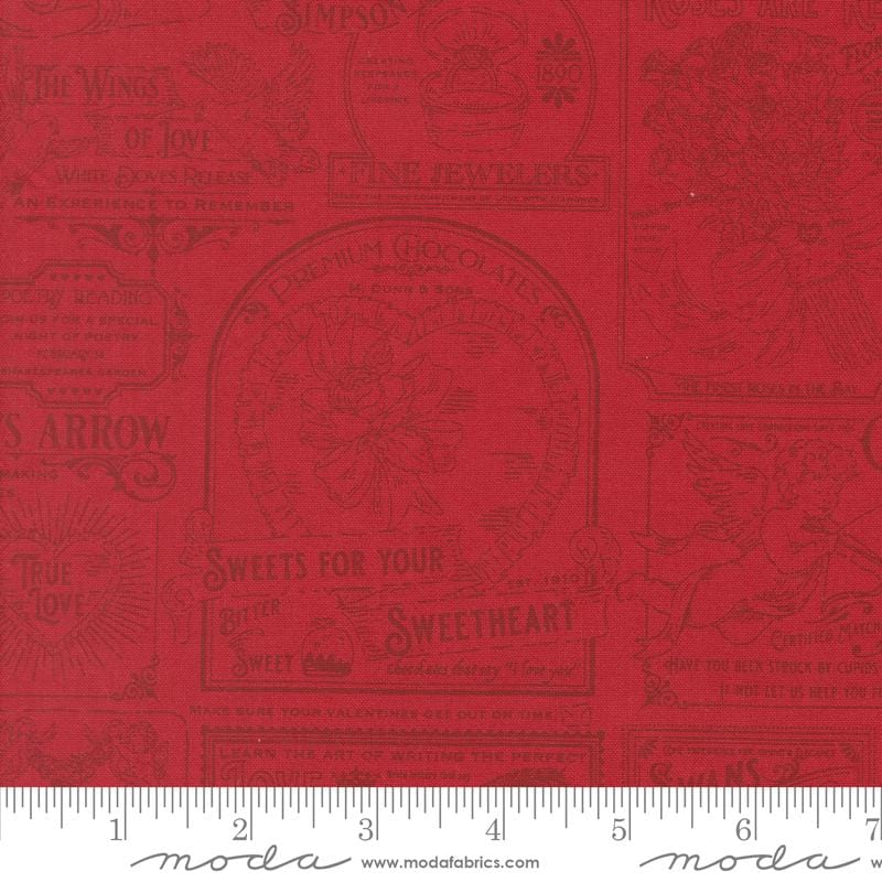a red fabric with various decorative text and illustrations, including phrases like "The Wings of Love", "The Arrow", "True Love", "Sweetheart", and "Sugar". The text and illustrations are arranged in a repeating pattern, creating a visually appealing and decorative design.