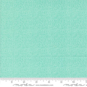 a ruler and a piece of fabric with a green background