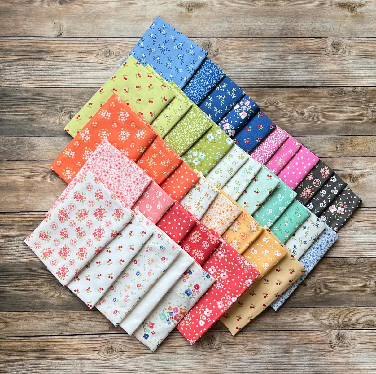 a bunch of different colors of fabric on a wooden surface