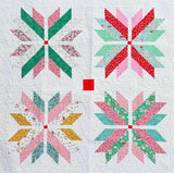 a quilted wall hanging with four snowflakes on it