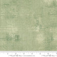 The image is a close-up of a textured green fabric with a ruler for scale.