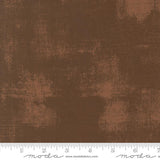 The image is a close-up of a brown fabric with a textured, distressed appearance.
