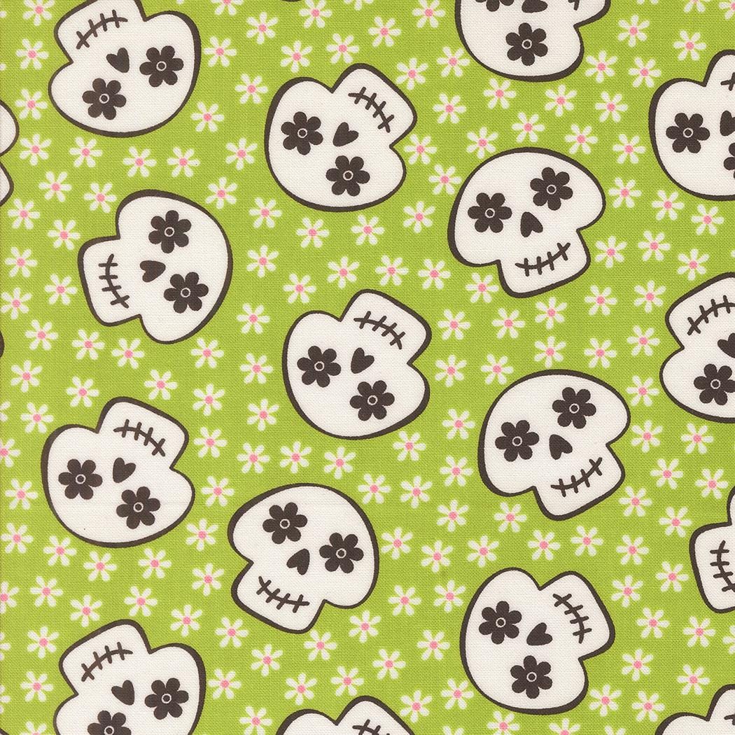 a repeating pattern of stylized skull faces on a green background with white flowers.