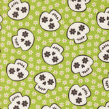 a repeating pattern of stylized skull faces on a green background with white flowers.