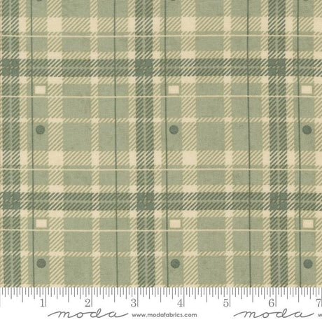 a fabric with a green and beige plaid pattern, featuring a repeating diagonal grid-like design. The fabric appears to be a textile or material with a plaid pattern, which is a type of textile design characterized by diagonal or crisscrossing lines. The fabric is displayed on a ruler for scale, indicating its size or dimensions.