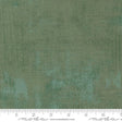 The image is a close-up of a textured green fabric with a ruler for scale.