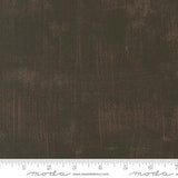 The image is a close-up of a textured fabric with a dark brown or black color.