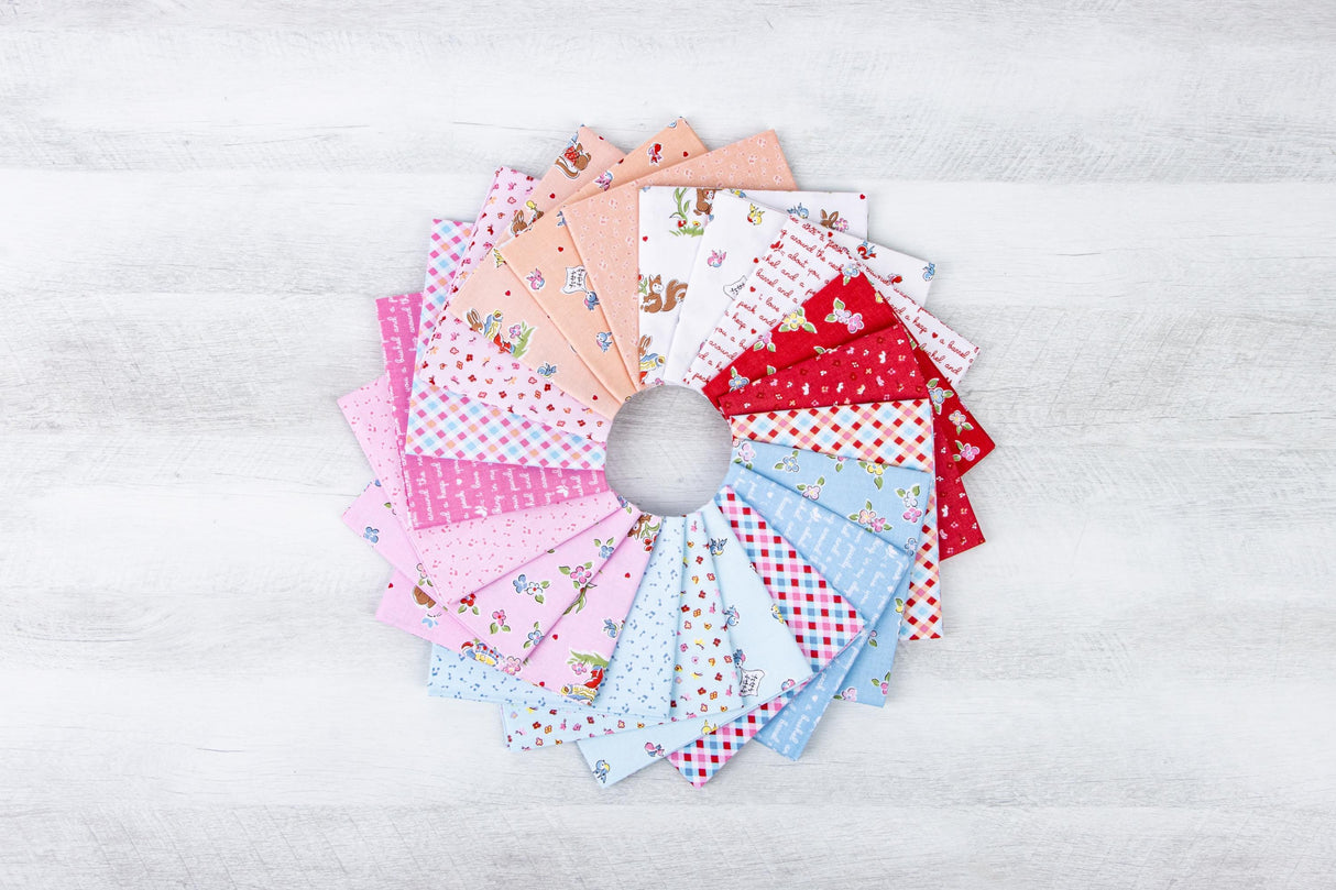 A circular arrangement of various fabric swatches in different colors and patterns, including pink, white, blue, and red, on a white wooden surface.