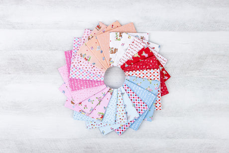 A circular arrangement of various fabric swatches in different colors and patterns, including pink, white, blue, and red, on a white wooden surface.