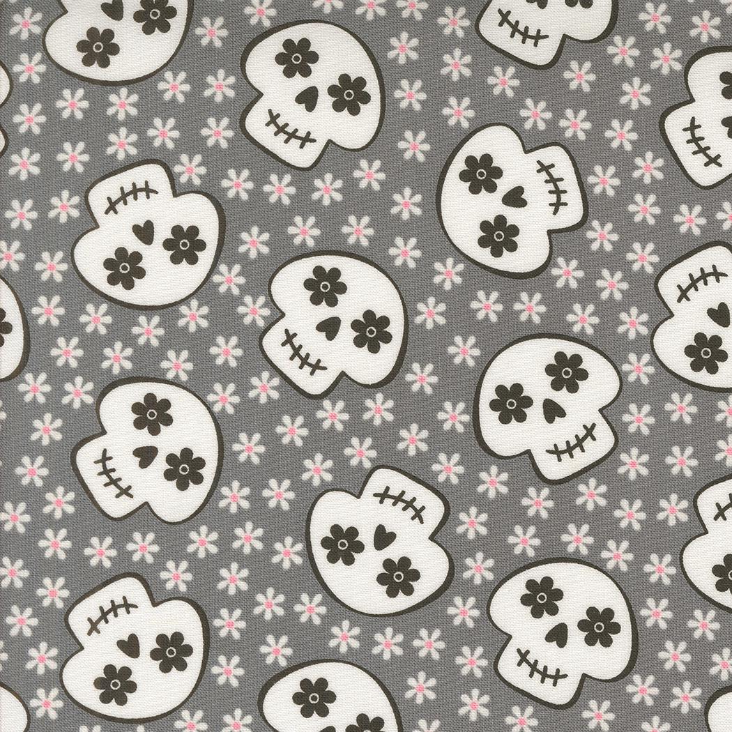 a repeating pattern of black and white skull faces against a gray background with small white flowers scattered throughout.