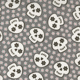 a repeating pattern of black and white skull faces against a gray background with small white flowers scattered throughout.