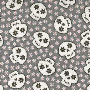 a repeating pattern of black and white skull faces against a gray background with small white flowers scattered throughout.