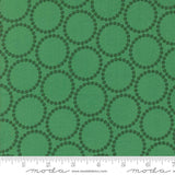 The image is a close-up of a fabric with a repeating pattern of green circles on a dark green background.