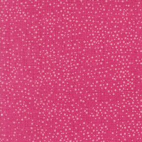 The image is a close-up of a pink fabric with small white dots or specks scattered across it, creating a textured and speckled appearance.
