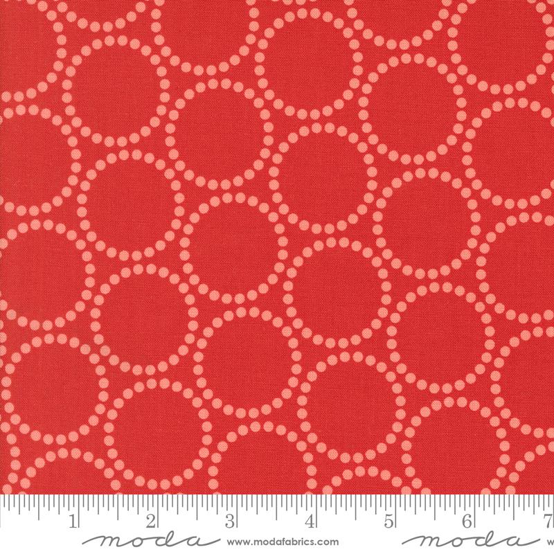 a close-up view of a red fabric with a repeating pattern of white circles on it. The fabric appears to be a fabric with a bold, geometric design.