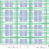 The image is a fabric with a repeating pattern of purple and green plaid squares. The pattern is composed of diagonal lines connecting the squares, creating a visually appealing and textured design. The fabric appears to be made of a soft, plush material, suitable for clothing or home decor items.
