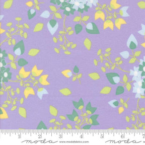 The image is a fabric with a purple background and a repeating pattern of green and yellow leaves and flowers.