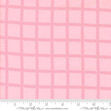 a pink fabric with a repeating pattern of pink squares and thin pink lines, creating a checkered or plaid design.