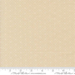 The image is a fabric sample with a light beige pattern, featuring small white dots or stars. The fabric is displayed on a ruler for scale, indicating its size.
