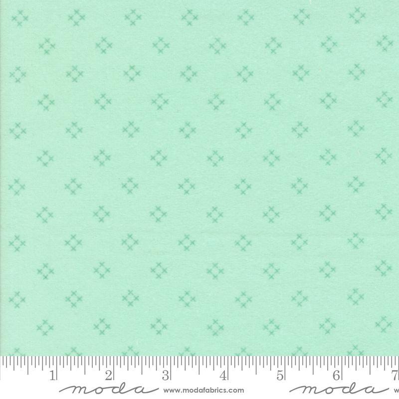 The image is a fabric with a repeating pattern of small green diamond shapes.